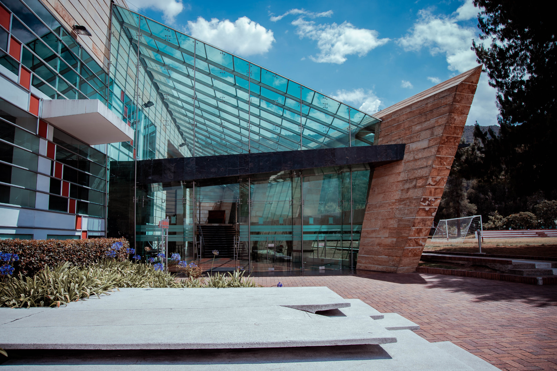 Campus Norte UNICOC: edificio de vidrio y piedra con fachada inclinada